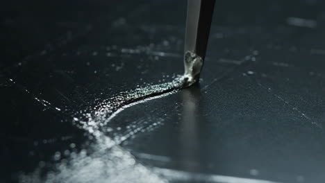close-up of a sharp object scratching a dark surface