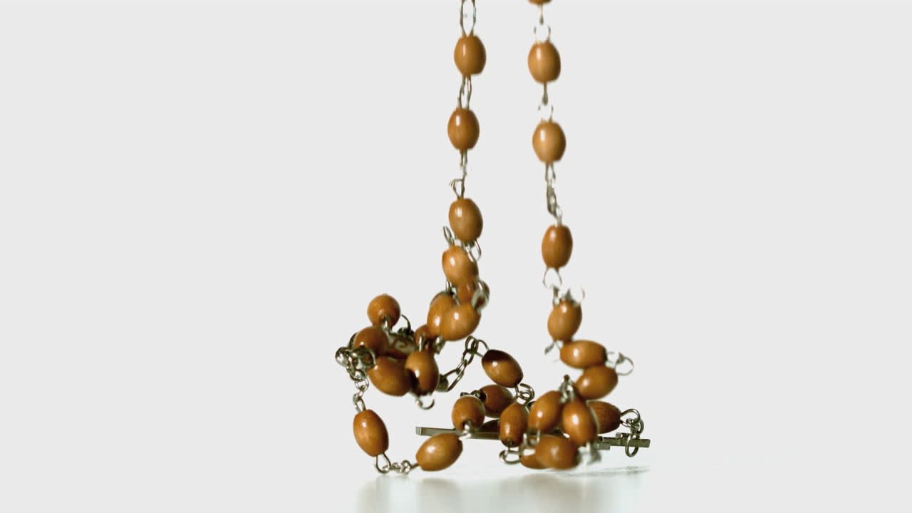 Rosary beads falling onto white surface