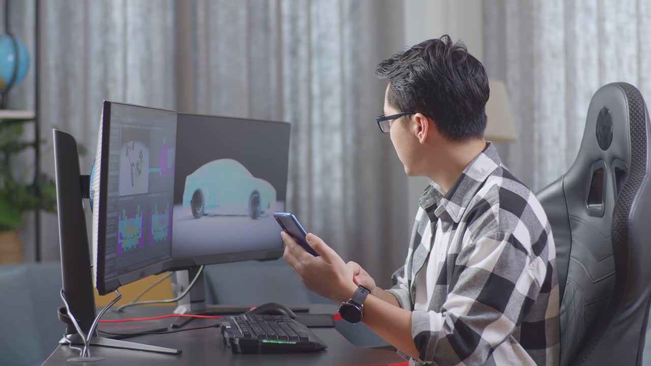 Side View Of Asian Male Automotive Designer Comparing The 3D Model Of Ev Car On The Desktop Computers To The Photo On His Smartphone In The Studio