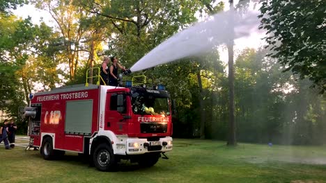 camión de bomberos alemán rociando agua para niños y árboles en un caluroso día de verano-3