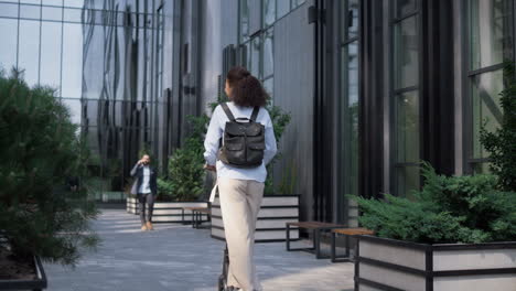 Office-manager-riding-kickscooter-downtown-district-rear-view.-Green-transport.