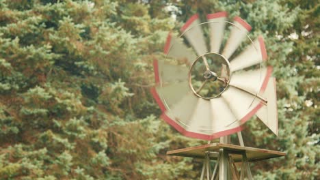 small windmill spinning in a backyard surrounded by trees