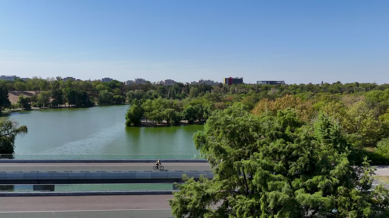 Bright Drone View of Tineretului Park, Showcasing a Bridge and Verdant Surroundings, Bucharest, Romania