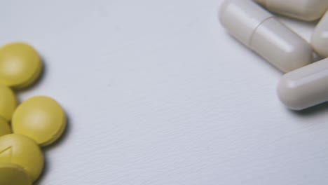 motion above piles of pills and capsules on light surface