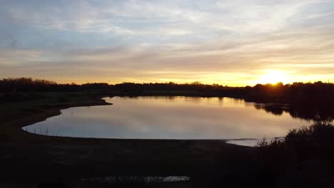 Paisaje-De-Lago-Tranquilo-Con-Puesta-De-Sol-Dorada,-Vista-Aérea-De-Drones