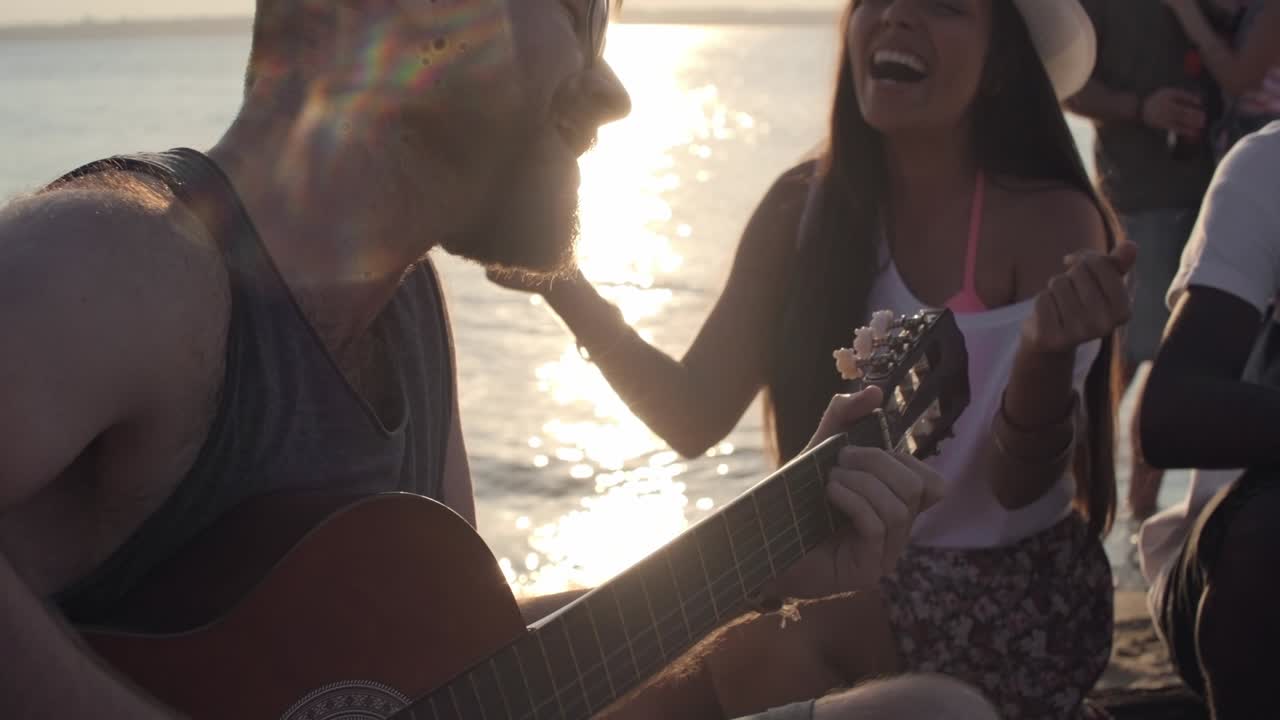 hombre tocando la guitarra para amigos en la playa