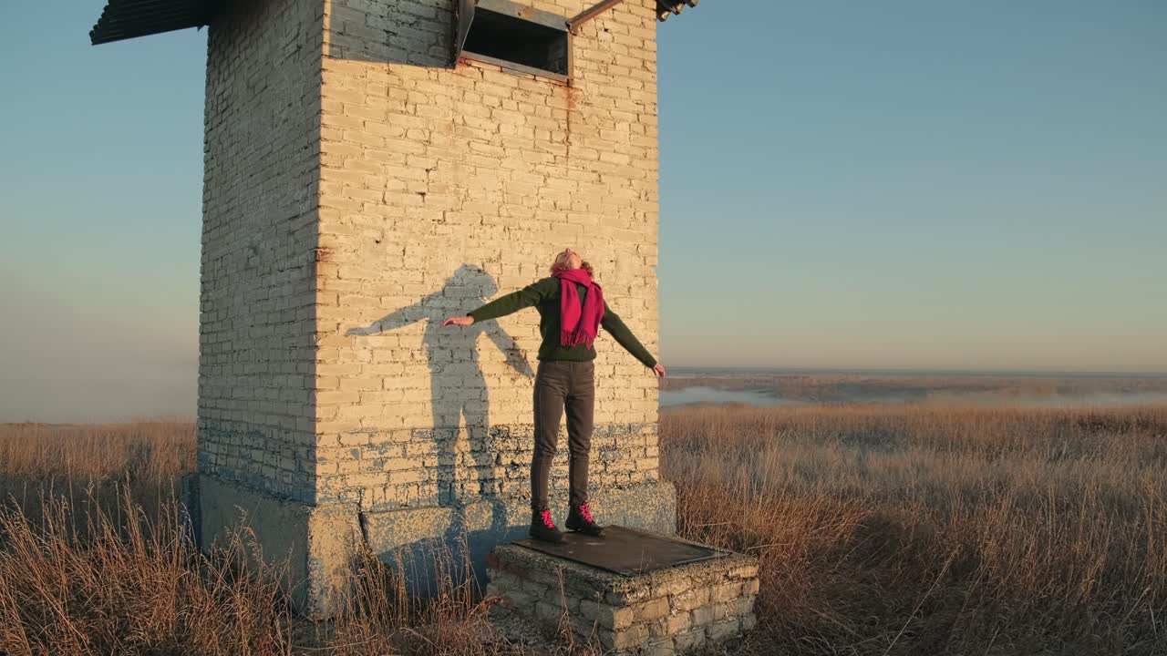 Woman standing on an old tower at sunrise in a foggy landscape