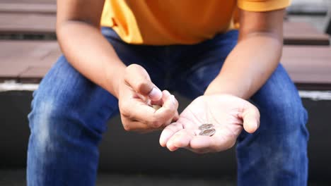 person sitting on a bench with coins in their hand