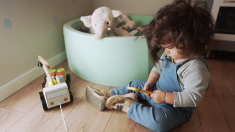 adorable young boy with long hair sitting while playing with smartphone at home - close up hand held