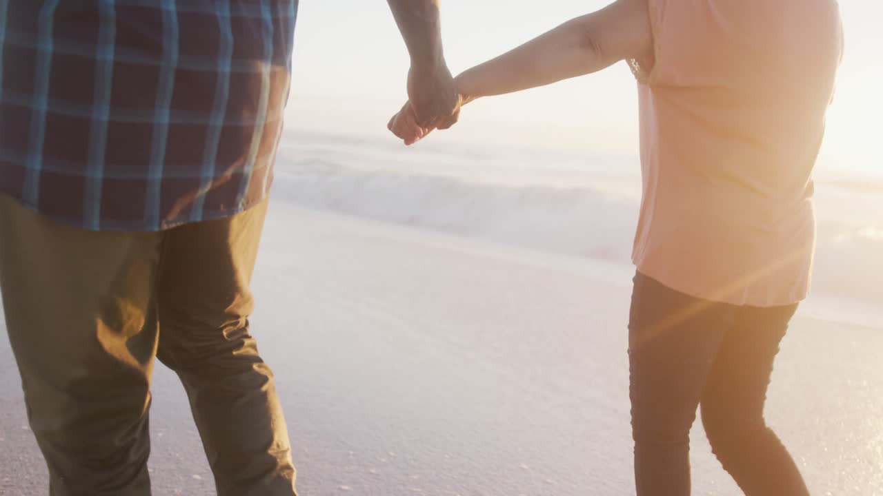 아프리카계 미국인 부부가 손을 잡고  ⁇ 은 해변에서  ⁇ 고 있습니다.