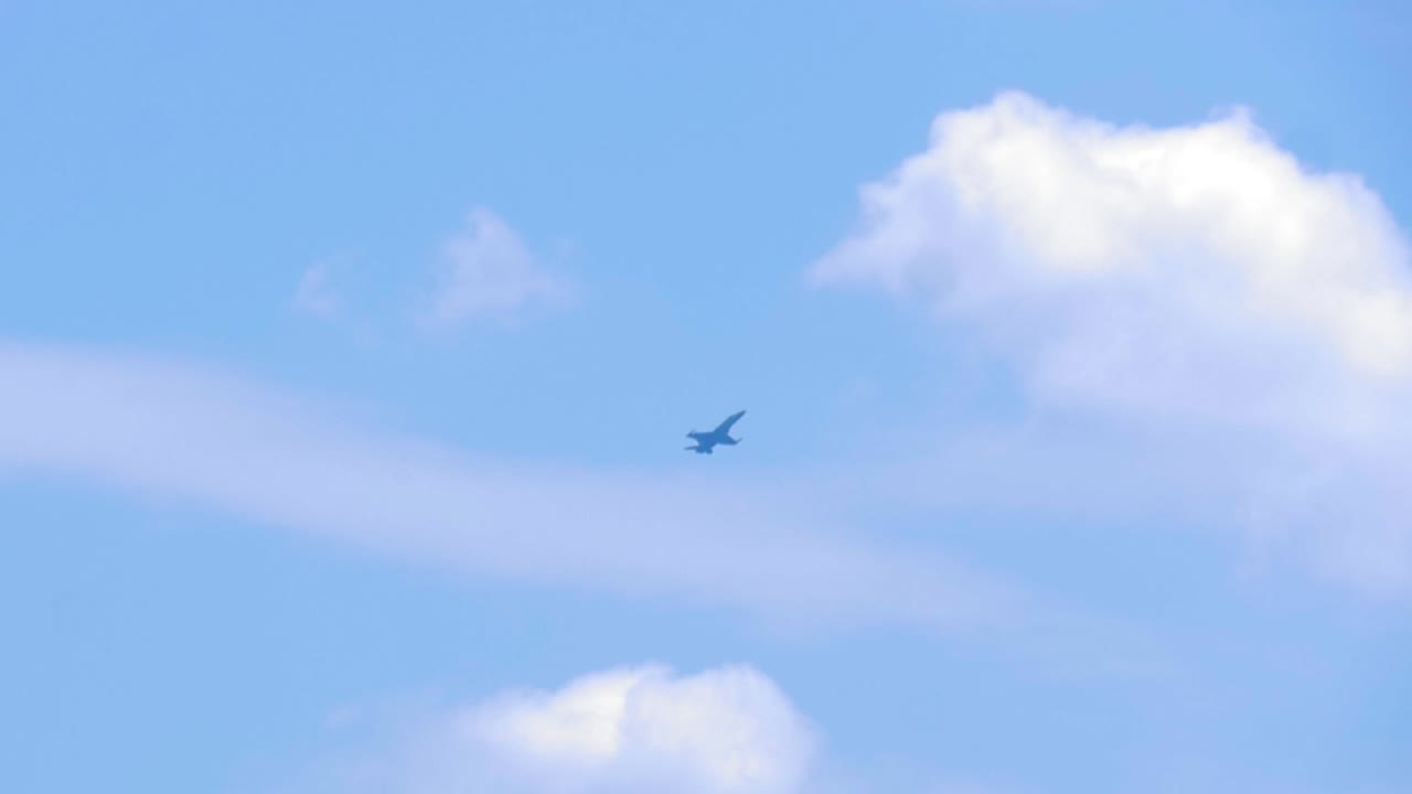 Rare slow motion footage of an Australian F-A-18 Super Hornet flying hovering in the sky on a cloudy day. We see the jet fighter hover in the air against the blue sky