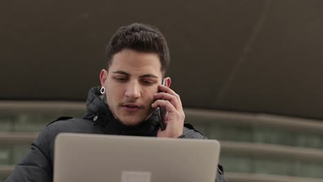 Front-view-of-businessman-talking-on-phone-and-using-laptop