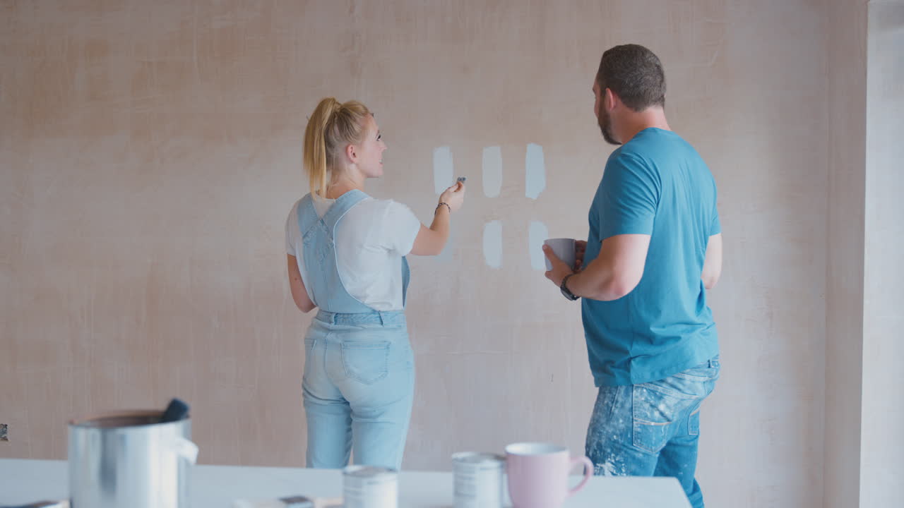 Couple Renovating Kitchen At Home Painting Tester Paint Colour Strips On Wall