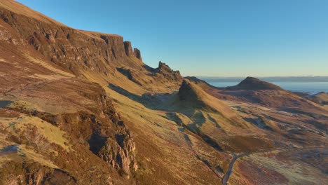 flying over cliff edge towards sloping ancient landslip cliffs and spires in early morning