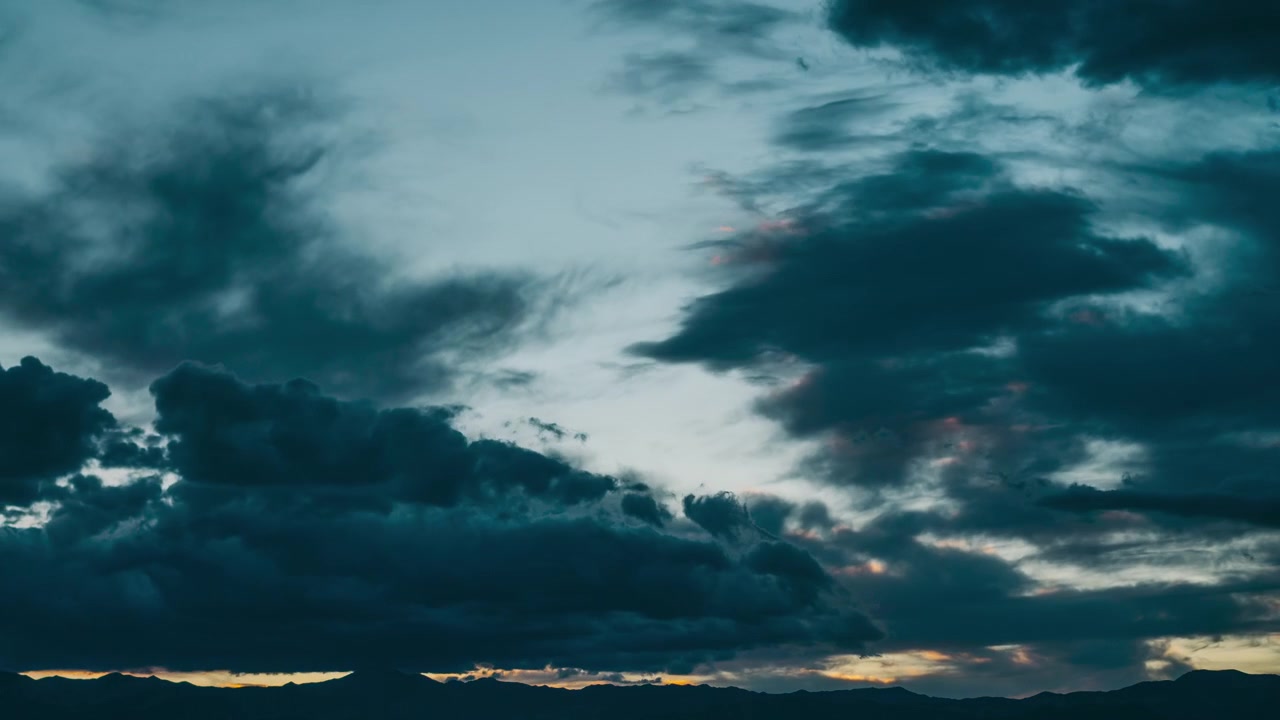 Time Lapse of Dramatic Clouds Moving Over Mountains at Sunset to Night
