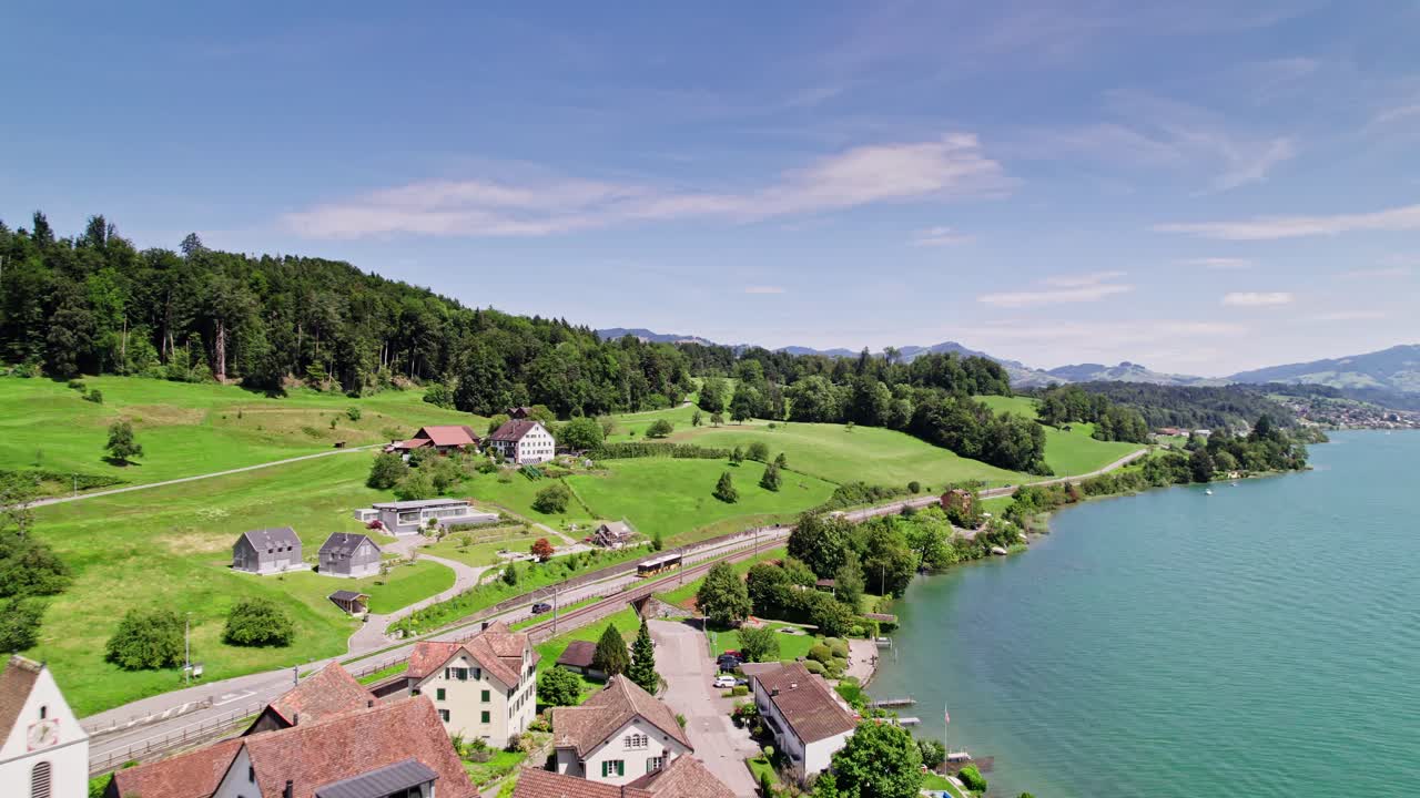 vuelo aéreo sobre un pequeño pueblo llamado bollingen en el lago superior en suiza - hermosos alpes de montaña y coches en la carretera costera durante un día soleado en la naturaleza - suiza,europa