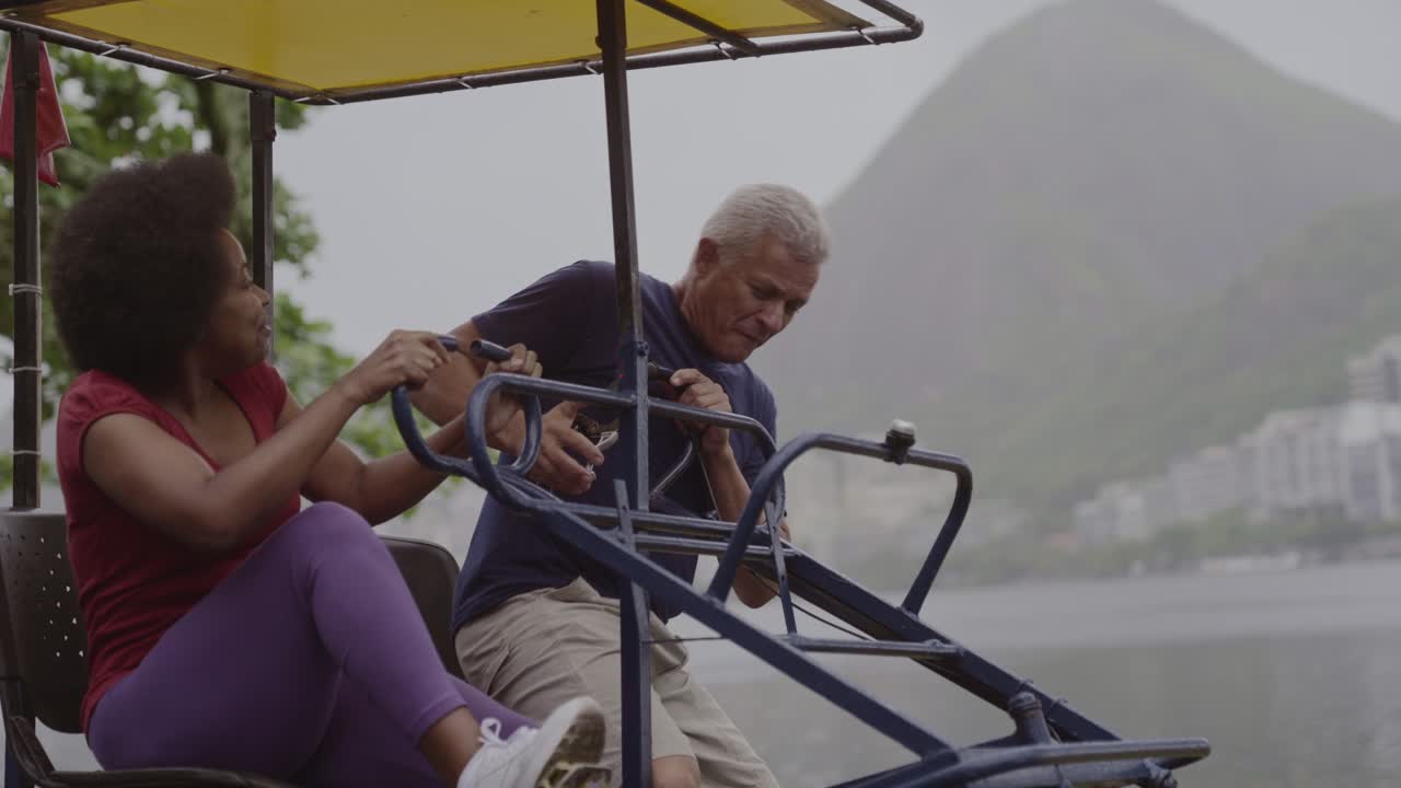 Senior couple enjoying a pedalo ride on a lagoon with a mountain backdrop
