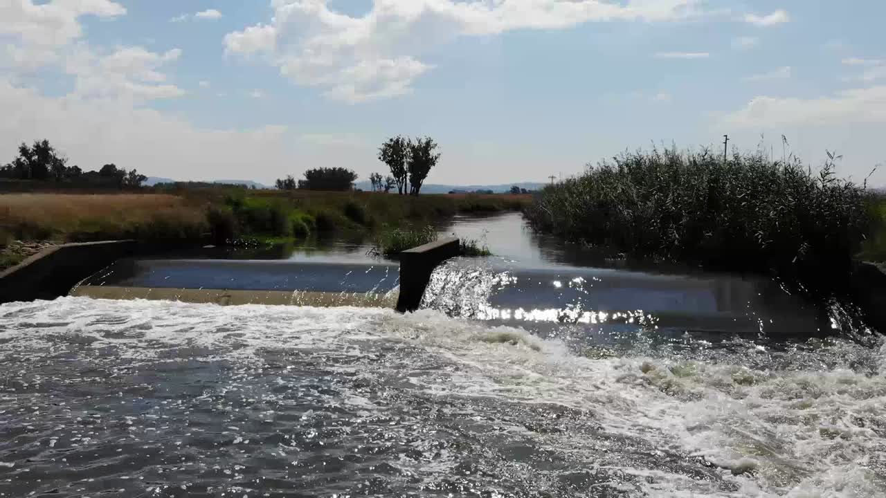 toma aérea de un dron del río que fluye bajo un puente remoto de grava en johannesburgo, sudáfrica