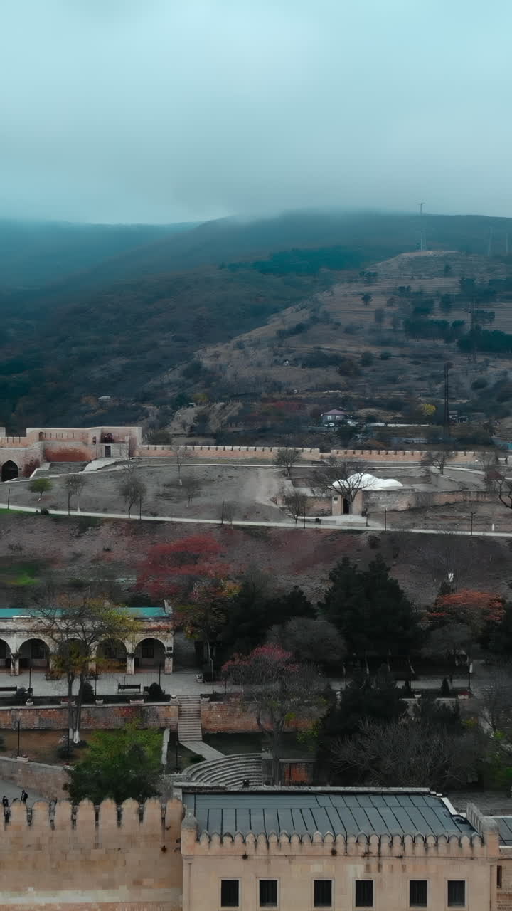 Vista aerea di un'antica fortezza e di una città murata tra montagne nebbiose