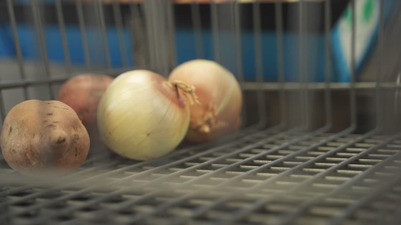 Shopper hand placing onions in shopping cart at a grocery store in Minnesota, USA.