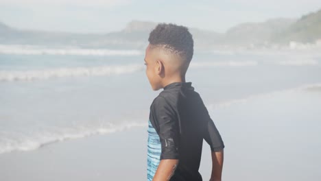 african american young boy jumping and enjoying at the beach