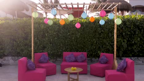 a side sliding shot of a pergola decorated with lanterns, couches and a table