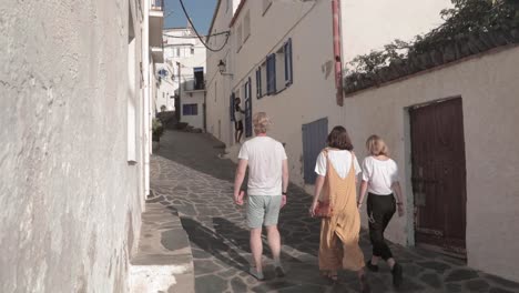slow motion, three friend tourists walking up narrow european alleyway in spain