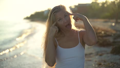 closeup en cámara lenta de una mujer madura retroiluminada señalando su cabello gris y riendo, celebrando su edad