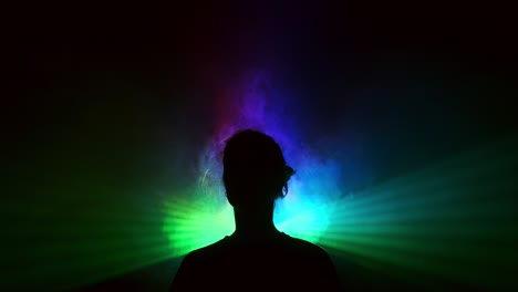 image of young girl on light background of different colors moving in the dark. smoke fills the triangle with the girl's head. projector.