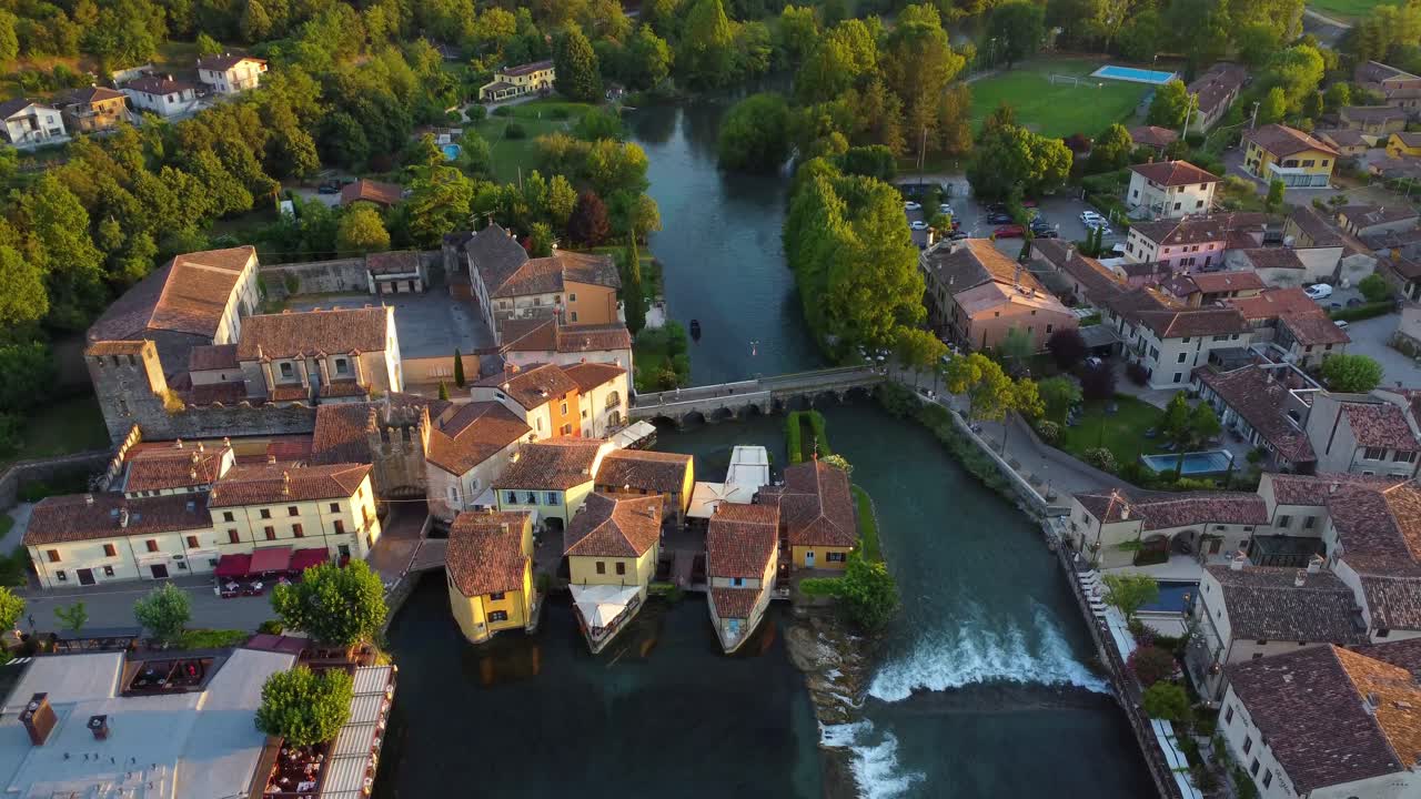 Aerial view of Borghetto sul Mincio at golden hour. This iconic medieval village in Veneto is built over water, with mills, stone bridges, and riverside charm near Lake Garda.