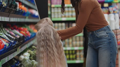 a mother in a protective mask with two children is buying groceries at the supermarket. buying food vegetables and fruits with children