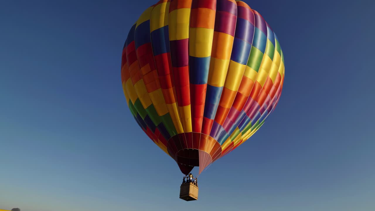 Una vivace mongolfiera fluttua sopra un campo di girasoli. Ripreso da un'angolazione bassa, il video