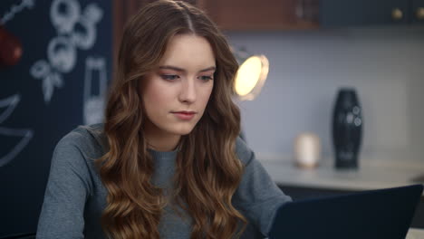 Portrait-of-young-businesswoman-working-laptop-computer-at-home-kitchen.