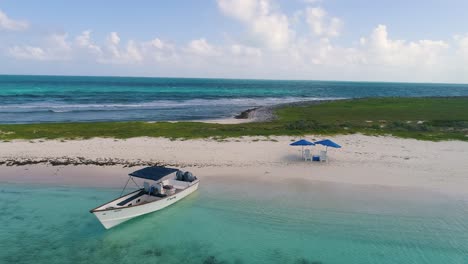 TURN-AROUND-ROMANTIC-SUNSET-CARIBBEAN-ISLAND-WITH-BOAT-AND-TWO-BEACH-CHAIRS