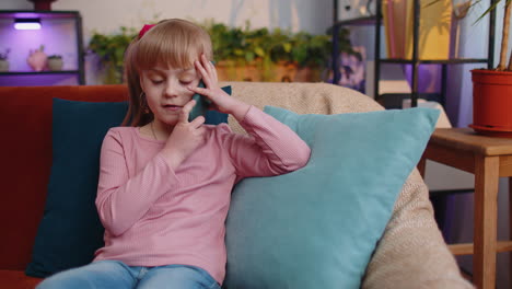 Girl-kid-enjoying-conversation-on-mobile-phone-with-friend-relaxing-sitting-on-couch-at-home-alone