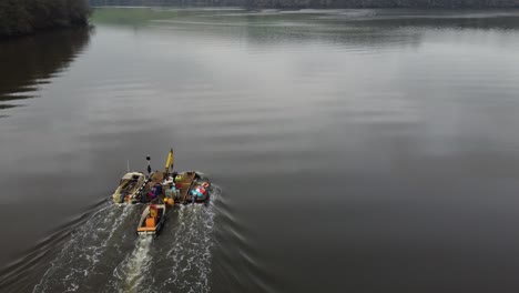 Ein-Vorwärtsfliegendes-Luftvideo,-Das-Einen-Schlepper-überfliegt,-Der-Einen-Lastkahn-Schiebt,-Der-Andere-Wasserfahrzeuge-Schleppt-Und-Eine-Landschaft-Enthüllt