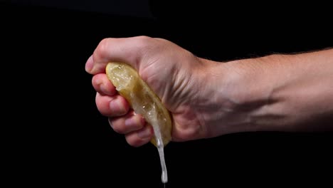 closeup of person's hand squeezing a juicy lemon