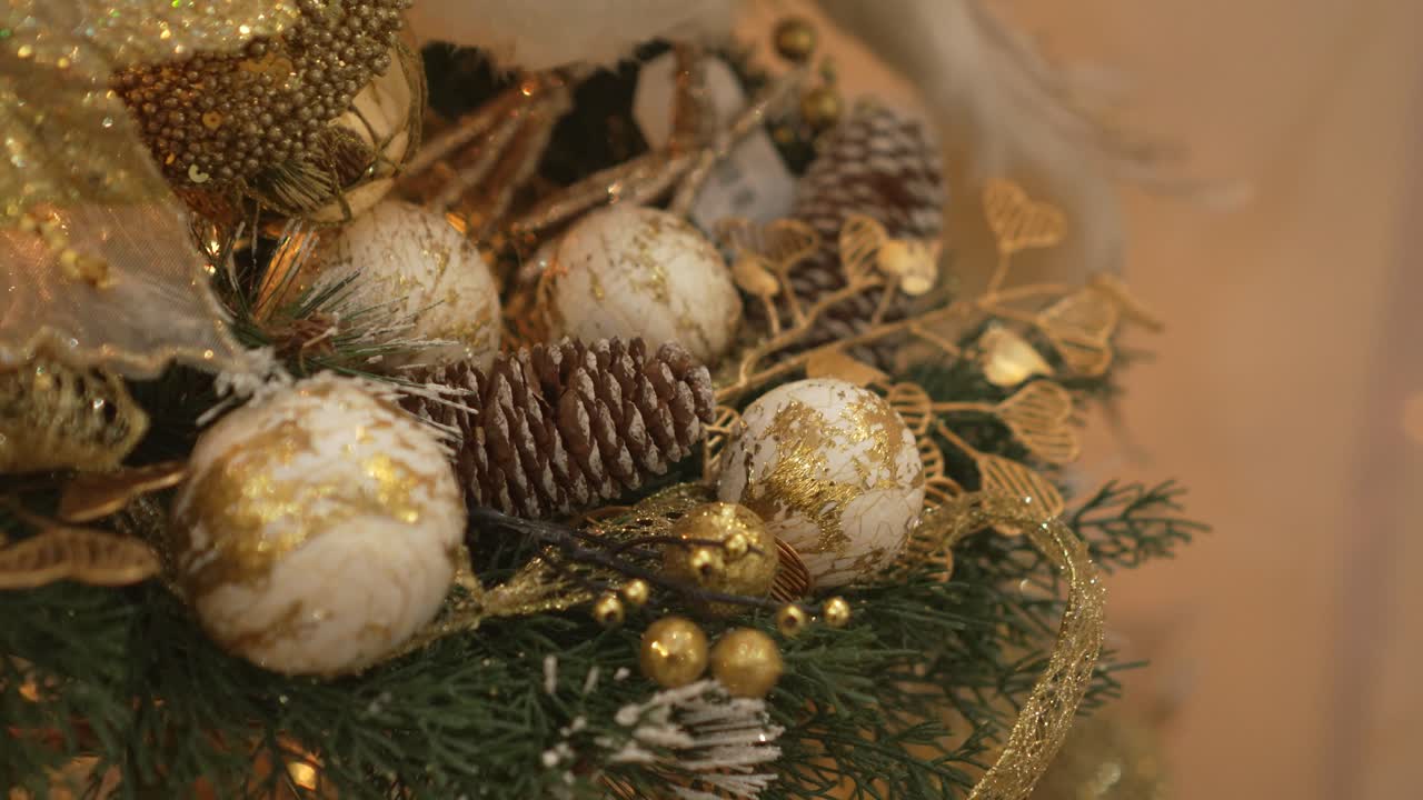 Close-up of Christmas tree with gold ornaments. The tree is illuminated with lights. 4k.