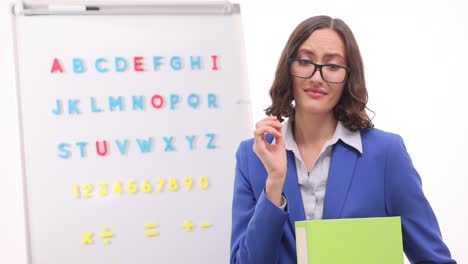 professional woman in classroom with alphabet and numbers board