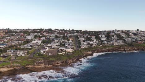 aerial view flying from ocean to beachfront homes. waterfront residential property in sydney’s eastern suburbs, australia – coastal living and oceanfront real estate footage