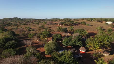 forward flying cinematic shot of chidenguele village showcasing traditional african huts and plantations