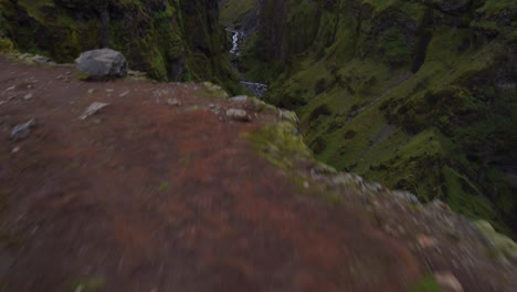 cascada del cañón que se eleva rápidamente toma de un excursionista de chaqueta roja admirando la vista del cañón verde