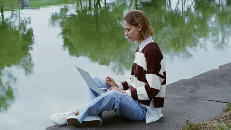 woman working on laptop by the pond