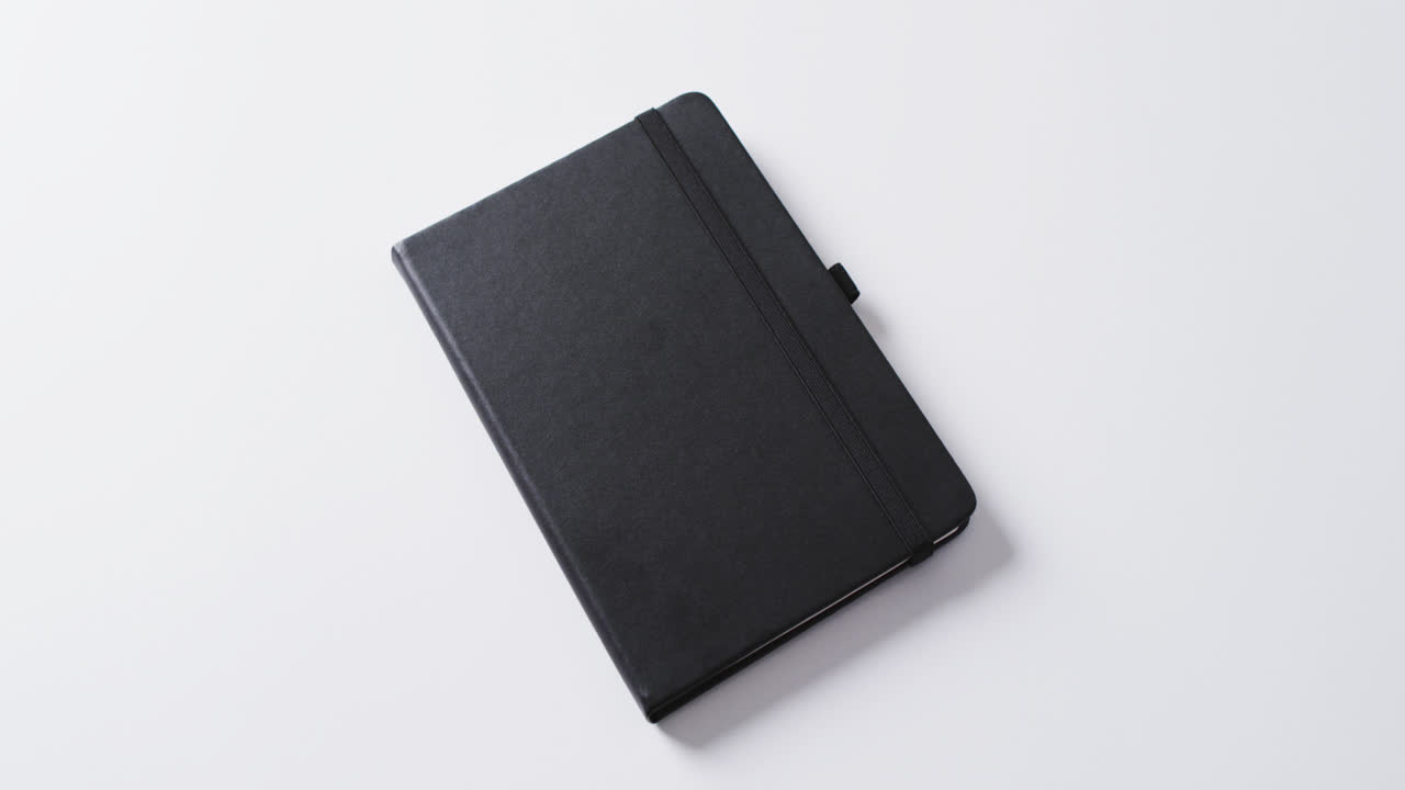 Close up of closed black notebook with copy space on white background in slow motion