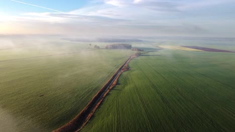 Volando-Sobre-Hermosos-Y-Verdes-Campos-Agrícolas-Hacia-El-Bosque-Temprano-En-La-Mañana-Con-Niebla-Alta