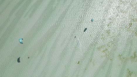 Draufsicht-Tracking-Aufnahme-Eines-Kiteboarders,-Der-An-Einem-Hellen,-Sonnigen-Tag-über-Tropische-Strandschwärme-Surft