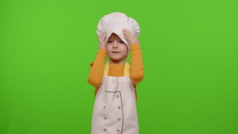 Child-girl-kid-dressed-as-professional-cook-chef-smiling,-crosses-arms-and-looks-intently-at-camera