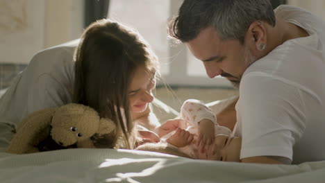 happy parents in bed on sunday morning playing with their cute baby girl and laughing