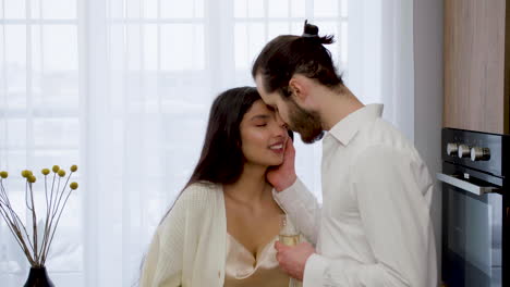 una pareja joven besándose en la cocina.