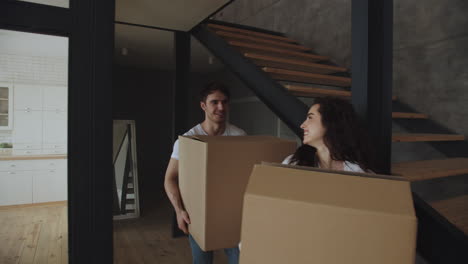 retrato de una joven pareja casada con cajas caminando en casa.